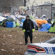 Un homme se tient debout au milieu d'un campement comptant plusieurs tentes.