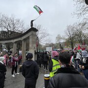 Un rassemblement propalestinien avec des drapeaux et des personnes portant des keffiehs. 