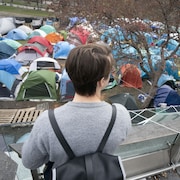 Une personne regarde les tentes sur le campus d'un point de vue surélevé.
