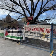 Des manifestants tiennent des affiches avec des messages comme « Arrêtez d'armer Israël ».