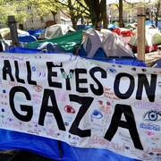 Un campement propalestinien caché par une grande toile, où il est écrit All eyes on Gaza.                         