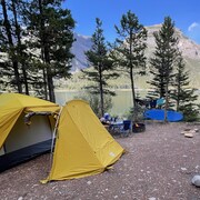 Un emplacement de camping avec une tente et un hamac au bord d'un lac
