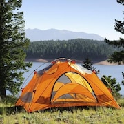 Une tente jaune est installée près d'un lac en montagne.
