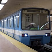 Une rame de métro bleue arrive dans une station.