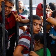 Des enfants massés derrière une barrière en métal.