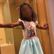 La petite fille, qui porte un déguisement de princesse et des oreilles de chat, prend la pose dans le cadre d'une porte donnant sur une salle de bain. Son visage est flouté.