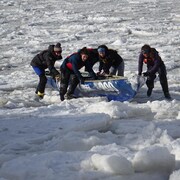 Les membres d'une équipe de canot à glace de l'UQAR poussent leur embarcation sur la banquise. 