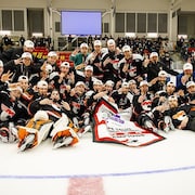 Les joueurs qui prennent une photo d'équipe sur la glace après la victoire.