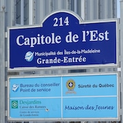 Une pancarte où il est indiqué que le Capitole de l'Est héberge des services de la Sûreté du Québec de la Maison des jeunes, de Desjardins et de la Muncipalité des Îles-de-la-Madeleine.