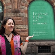 Une femme se tient devant une publicité de pétrole vert.