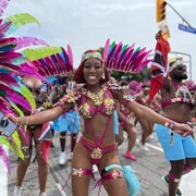 Une danseuse en costume sourit et pose pour une photo pendant le grand défilé du carnaval des Caraïbes à Toronto samedi.