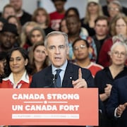 Le chef libéral Mark Carney parle lors d'une conférence de presse devant des candidats libéraux assis derrière lui.