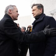 Mark Carney s'entretenant avec Pierre Poilievre avant une cérémonie au Monument national de l'Holocauste, le lundi 27 janvier 2025 à Ottawa.