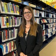Carole-Ann Demers pose devant des étagères pleines de livres.