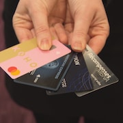 Une personne tient quatre cartes de crédit différentes.
