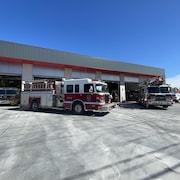 Deux camions de pompiers sont stationnés devant une caserne d'incendie.