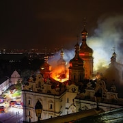En pleine nuit, des pompiers sont déployés devant une cathédrale, dont le toit est enflammé.