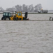 Des tracteurs roulent dans un champ inondé à Abbotsford, en Colombie-Britannique.