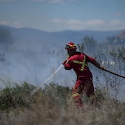 Un pompier arrose un amas de broussailles en feu dans les environs de Kamloops, en Colombie-Britannique, le lundi 5 juin 2023.