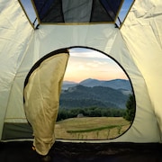 Une tente s'ouvre sur des montagnes.