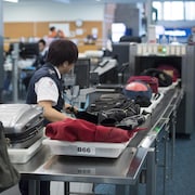 Des employés de l'Administration canadienne de la sûreté du transport aérien inspectent les bagages des voyageurs à un point de contrôle de l'Aéroport international de Vancouver, à Richmond, en Colombie-Britannique, le lundi 6 février 2017.