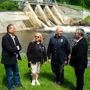 Trois hommes et une femme discutent devant le barrage Saint-Narcisse. 