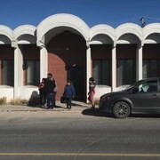 Un bâtiment devant lequel il y a des gens et une voiture.