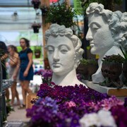 Des statuettes, des plantes et des gens dans un centre de jardinage.