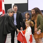 La juge serre la main d'une petite fille nouvellement canadienne.