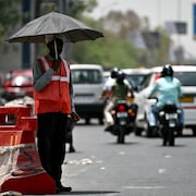 Un homme tient un parapluie dans le trafic.