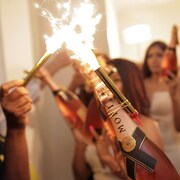 Des gens tiennent des bouteilles de champagne avec des feux de Bengale accroch&eacute;s.