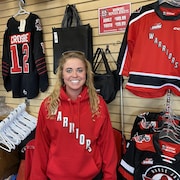 Cassidy Maier dans un magasin de Moose Jaw, en Saskatchewan, devant des chandails à l'effigie de l'équipe de hockey junior des Warriors, le 29 mai 2024.