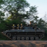 Des soldats circulent dans un char d'assaut.