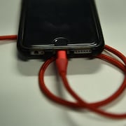 Un fil de chargement rouge est branché dans un iPhone.