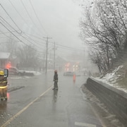 Des pompiers sur une rue inondée où une voiture est immergée.