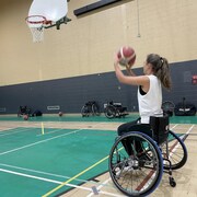 Une joueuse de basketball en fauteuil roulant prend un tir.