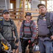 Une équipe de charpentiers prennent la pose devant une maison en construction.