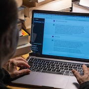Une personne assise devant un ordinateur portable pose des questions à ChatGPT en anglais, mais en faisant des fautes.