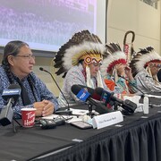 Les quatre chefs s'adressent aux médias, vêtus d'une coiffe traditionnelle.