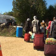 Des migrants se rendent au Canada par le chemin Roxham alors que des agents de la GRC les attendent de l'autre côté de la frontière. 