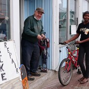 Une jeune fille, tout sourire, après que Gaston aie réparé son vélo.