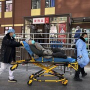 Deux infirmiers déplacent un homme sur une civière.