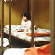 Une petite fille est assise sur un lit.