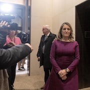 Chrystia Freeland sort d'une salle devant des caméras.
