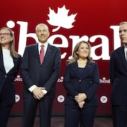 Quatre personnes posent sur une scène arborant le logo du Parti libéral du Canada.