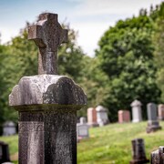 Une pierre tombale surplombée en gros plan dans un cimetière. 