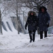 Une femme et un homme déambulent sur la rue Saint-Germain au centre-ville de Rimouski alors qu'il tombe de gros flocons de neige.