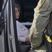 Claire Bell assise dans une voiture de police.