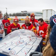 Des amateurs  des Flames de Calgary et des Jets de Winnipeg ont le sourire aux lèvres en jouant au hockey sur table.