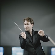 Le chef d'orchestre dirige un orchestre. Il tient sa baguette de chef. 